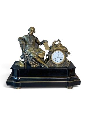 une statue représentant un homme assis sur une chaise, avec une horloge