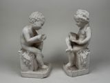pair of white marble statues of a boy and a girl reading a book