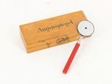 a wooden box with a red handle and a magnifying glass on it