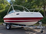 a white and red boat on a trailer in a parking lot