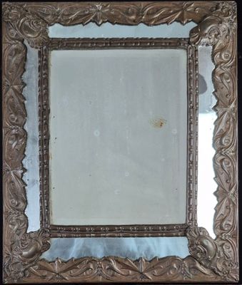 Miroir à parecloses en laiton repoussé à décor feuillagé.