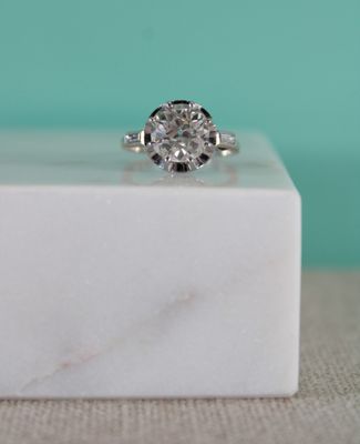 une image représentant une bague en diamant posée sur un bloc de marbre blanc