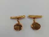 a pair of gold plated cufflinks with a scarnap on the front and a scarnap on the back