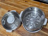 a stainless steel strainer with a lid on a wooden table
