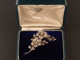 une broche ancienne en forme de fleur sertie de diamants, présentée dans un écrin en velours bleu