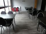 des tables et des chaises dans une pièce où est accrochée une horloge au mur