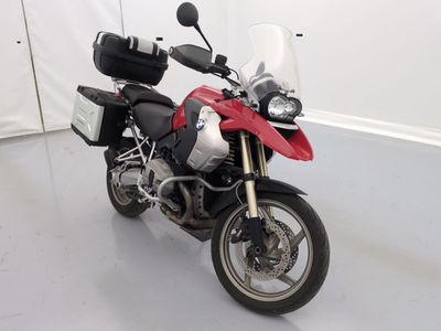 une moto rouge et noire garée dans une pièce blanche
