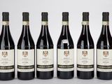 six bouteilles de vin sont alignées sur une surface blanche