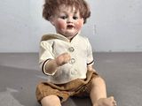 une petite poupée assise par terre, vêtue d'une veste