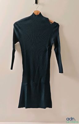 une robe à col roulé noire suspendue à un cintre accroché au mur