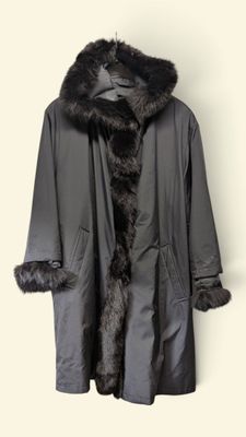 un manteau gris avec un col en fourrure noire, suspendu à un cintre contre un mur blanc