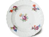 gros plan d'une assiette avec des fleurs sur une surface blanche