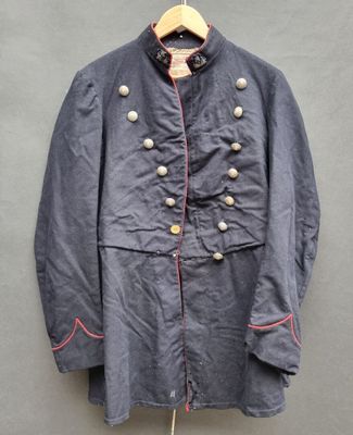 un vieux manteau militaire accroché à un cintre sur un mur