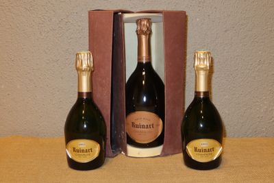 trois bouteilles de champagne posées sur une table à côté d'un carton de vin