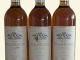 trois bouteilles de vin posées les unes à côté des autres sur une surface blanche