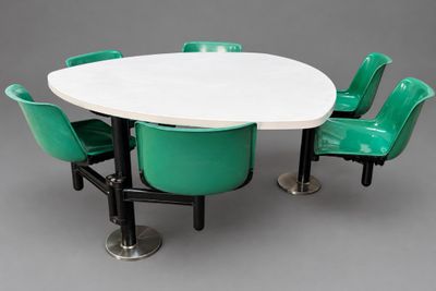 une table blanche entourée de quatre chaises vertes