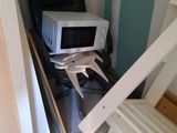 a microwave and a chair in the corner of a room