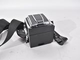 a black camera with a black strap on a white surface