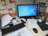 a desk with a computer, keyboard, calculator, and other office supplies on it
