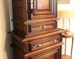 a tall wooden cabinet with a clock on top of it