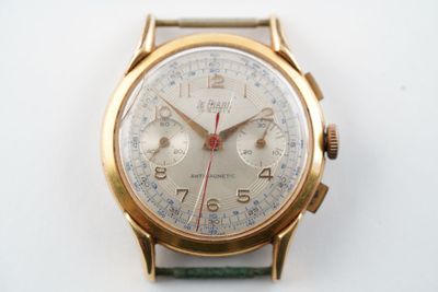 une montre-bracelet en or avec un bracelet vert sur une surface blanche