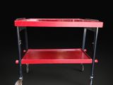 a red trolley on wheels against a black background