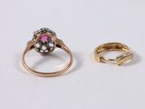 two gold rings and a pink stone ring on a white surface