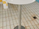 a white table with a silver base on a tiled floor