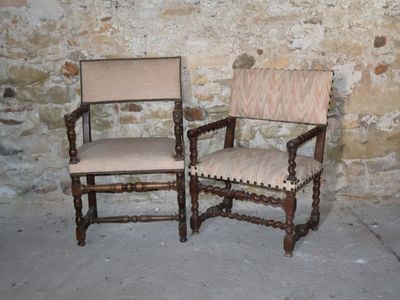 two chairs sitting next to each other in front of a stone wall