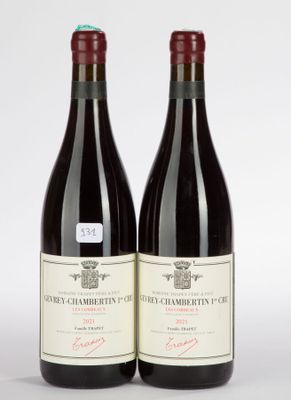 two bottles of red wine sitting next to each other on a white surface