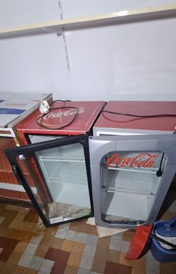 two small refrigerators sitting next to each other on the floor