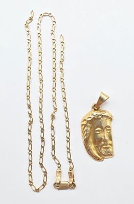 a close up of a gold necklace and a gold pendant on a white surface