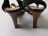 pair of women ' s black sandals with wooden heels on a white surface