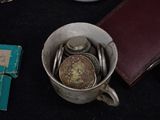 a cup with coins in it next to a book and a wallet