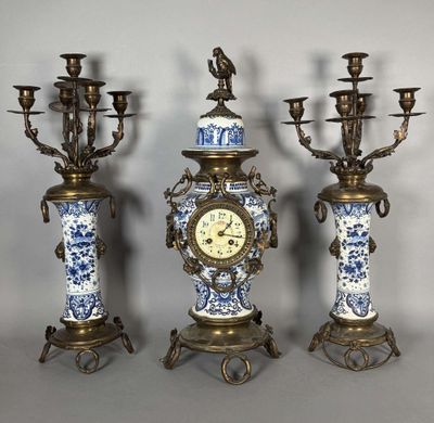 trois vases bleus et blancs sur lesquels est posée une horloge