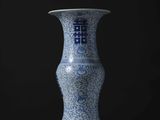 un vase bleu et blanc posé sur une table, sur fond noir