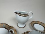 four pieces of china on a table with a pitcher and saucer