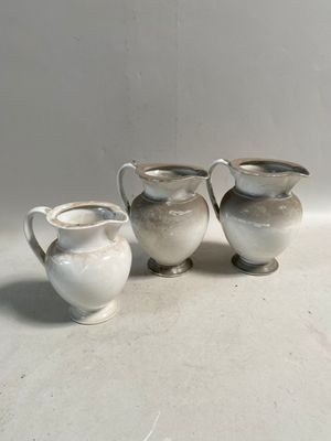 trois petits pichets blancs posés les uns à côté des autres sur une table
