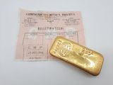 un vieux lingot d'or posé à côté d'un ticket de caisse sur une table