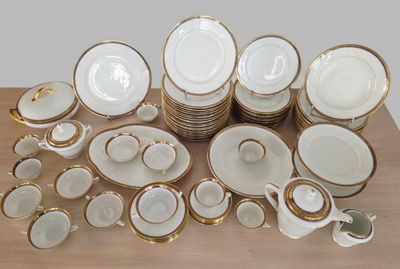 beaucoup d'assiettes et de tasses blanches et dorées sur une table