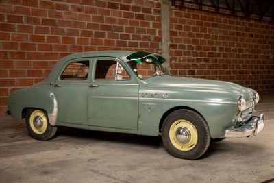 a green car parked in front of a brick wall