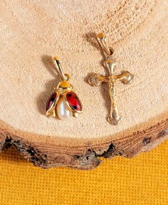 a close up of a cross and a ladybug pendant on a piece of wood