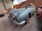 an old blue car parked in a garage next to other cars