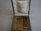 six spoons in a green case on a white table