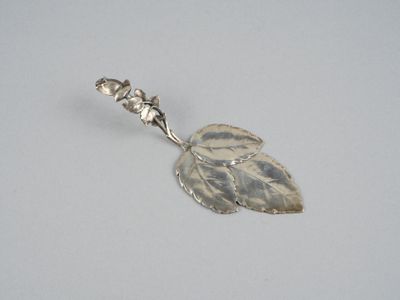 une cuillère en argent ornée d'une feuille, posée sur une table