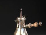 une cafetière ancienne en argent avec une poignée en bois, sur fond noir
