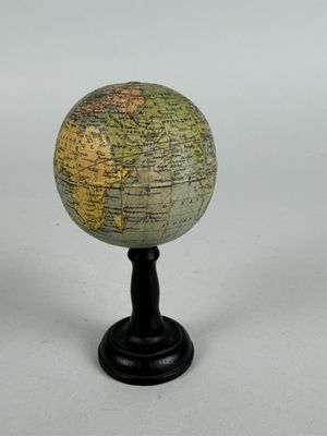 a small globe on a black stand on a white surface
