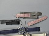 four different watches and a watch strap on a table