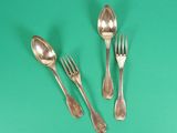three spoons, two forks and a spoon on a green surface