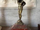 a statue of a boy holding a ball on his head